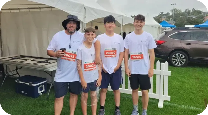 Cuatro participantes con dorsal posando antes de una carrera popular