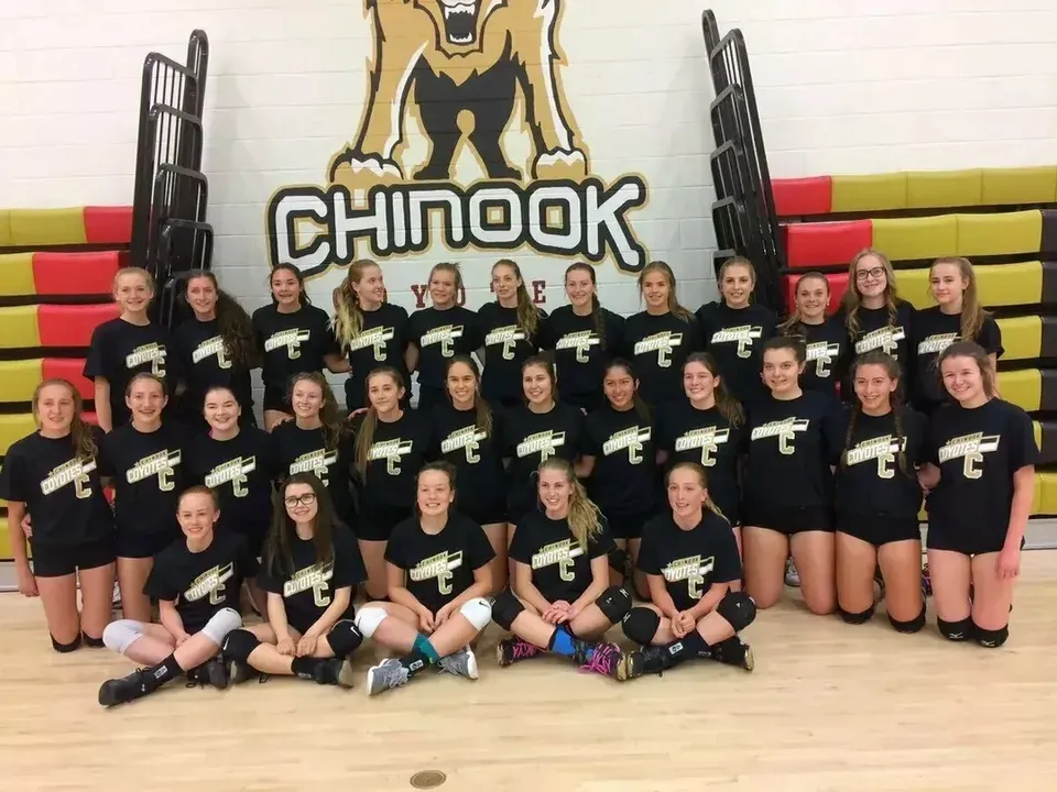 Un gruppo di giovani atlete della Chinook High School posa in palestra davanti a materassini e attrezzi.