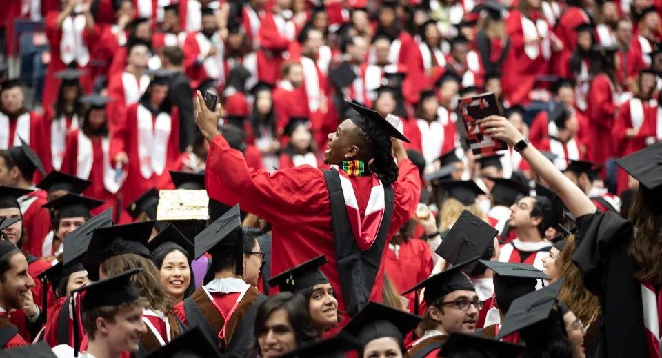 Un grande gruppo di diplomati in toga rossa festeggia alla cerimonia di diploma della Somervale School in un'aula interna.