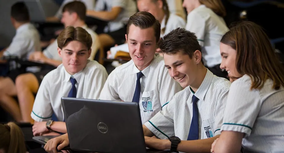 Un gruppo di studenti in divisa scolastica lavora insieme a un laptop al Burpengary State Secondary College.