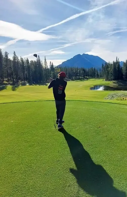 Studente gioca a golf su un campo verde con montagne sullo sfondo