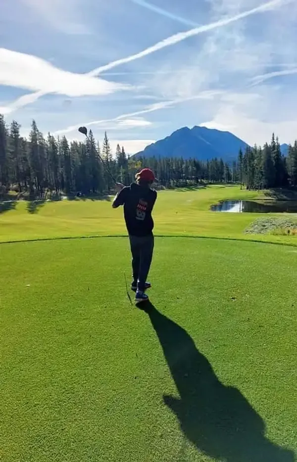 Studente gioca a golf su un campo verde con montagne sullo sfondo
