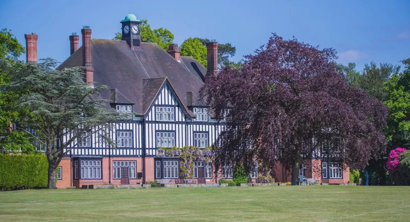 La villa in stile Tudor della Queenswood School è circondata da un verde lussureggiante e da un grande albero con foglie viola.