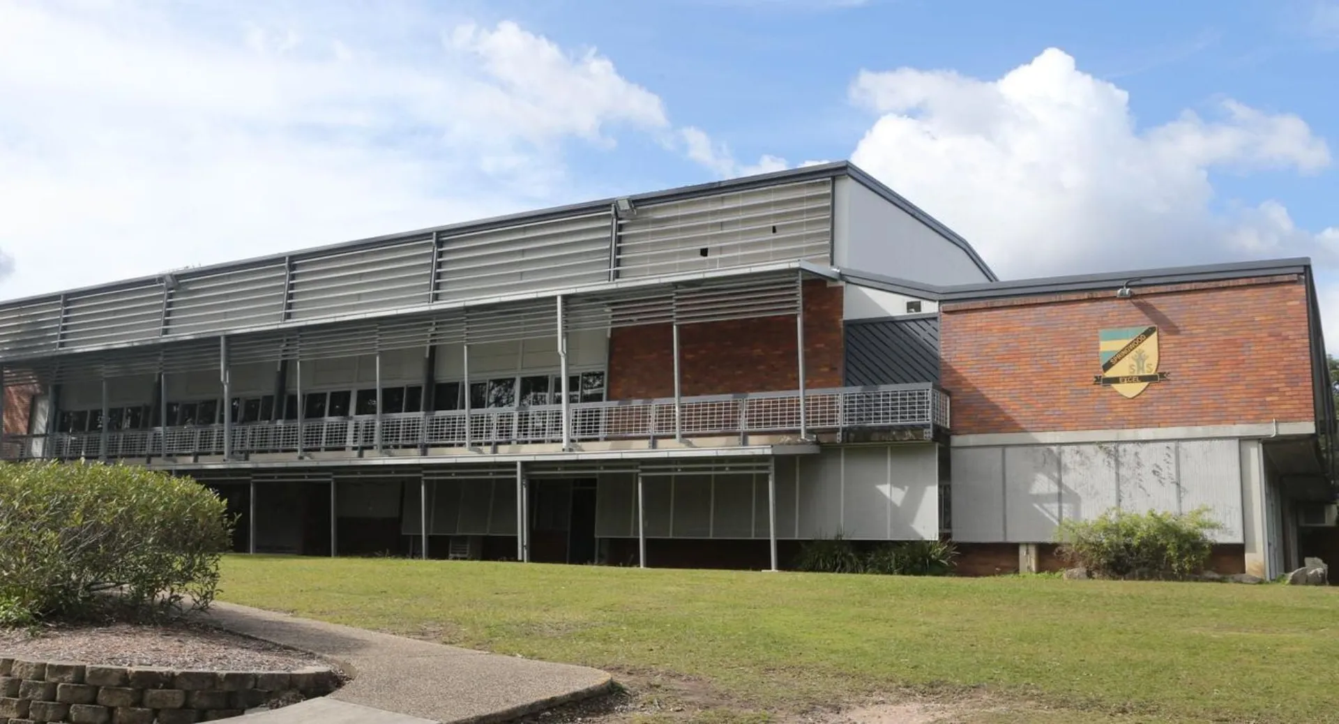 L'edificio moderno a più piani della Springwood School si trova su un prato sotto un cielo nuvoloso.
