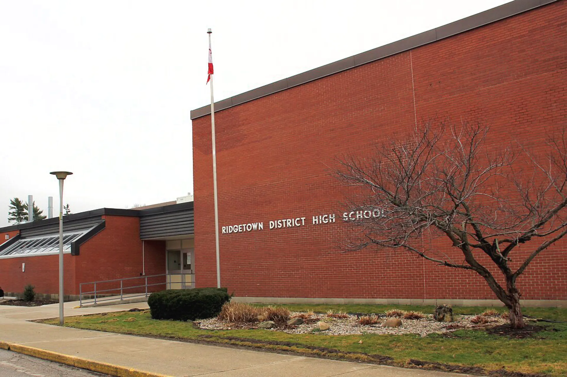 L'edificio in mattoni rossi della Ridgetown District High School è circondato da un'area esterna curata con un albero spoglio.