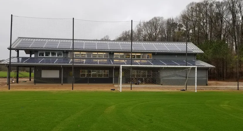Una porta da calcio sul campo in erba davanti a un edificio della The Barnes Academy con pannelli solari.