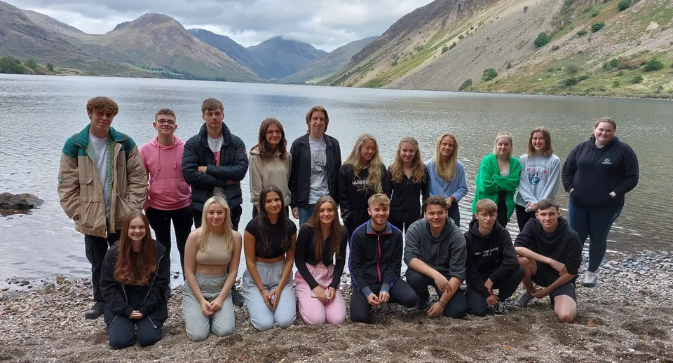 Studenti del Queen Elizabeth’s 6th Form insieme davanti a un lago di montagna con cime innevate.