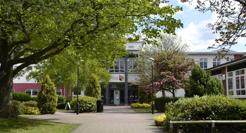 Un giardino ben curato con alberi in fiore e cespugli lungo un vialetto nel campus del Portsmouth College.