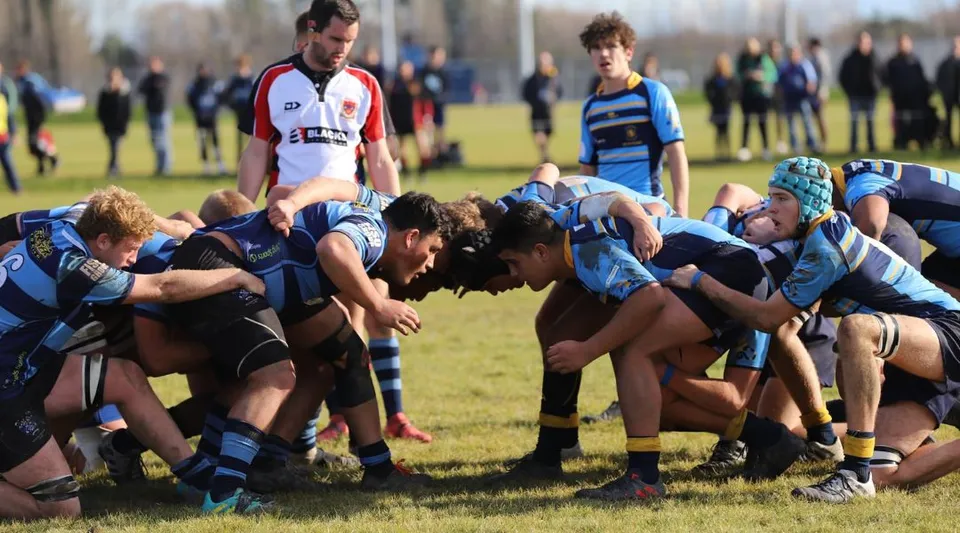 Giocatori di rugby della Shirley Boys' High School formano una mischia sul campo da gioco davanti agli spettatori.
