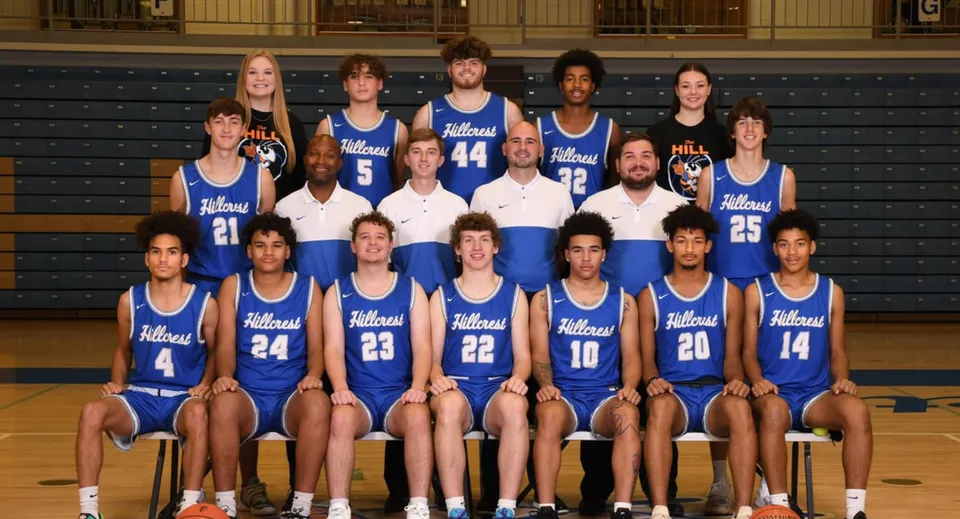 La squadra di basket della Hillcrest High School posa insieme in divisa blu nella palestra.