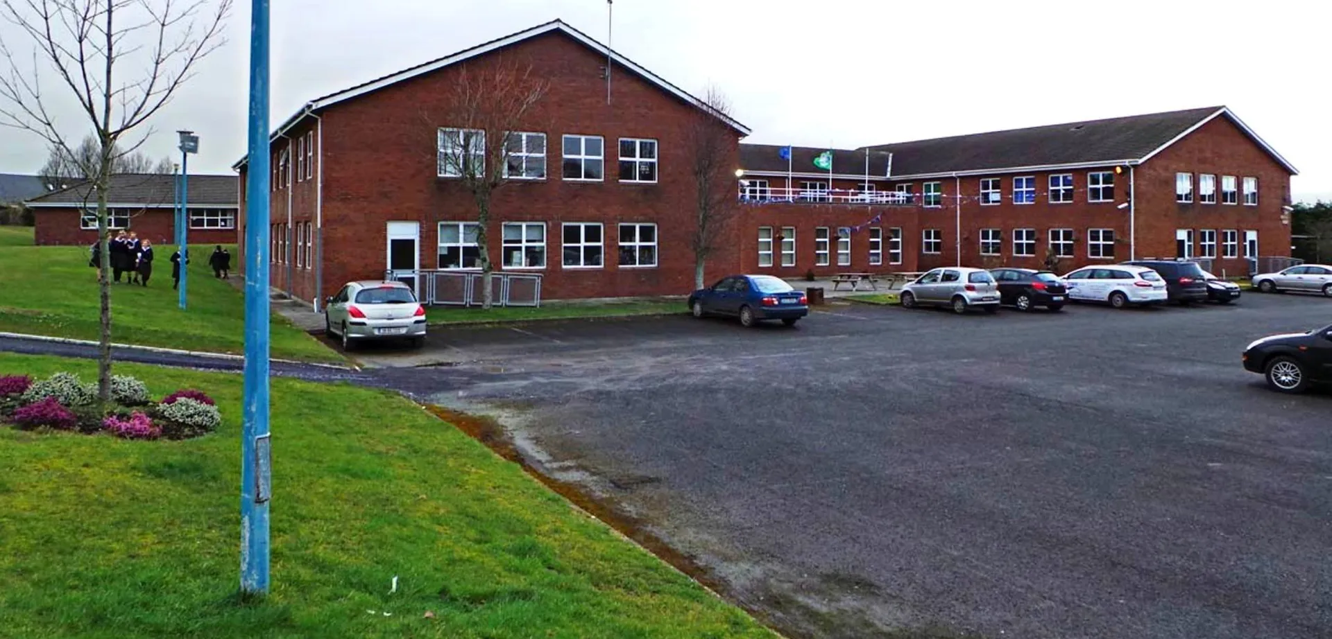 L'edificio in mattoni della Presentation Secondary School a Kilkenny con parcheggi e veicoli in primo piano.