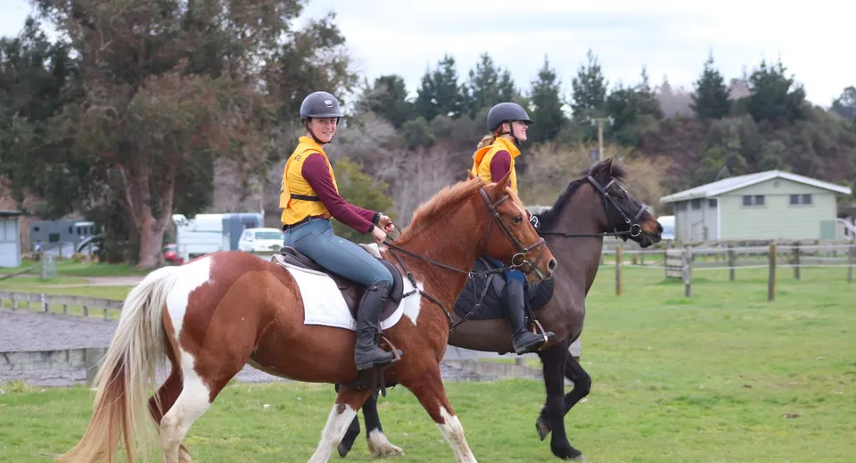Due persone montano a cavallo su un campo erboso nel campus del Waiuku College.