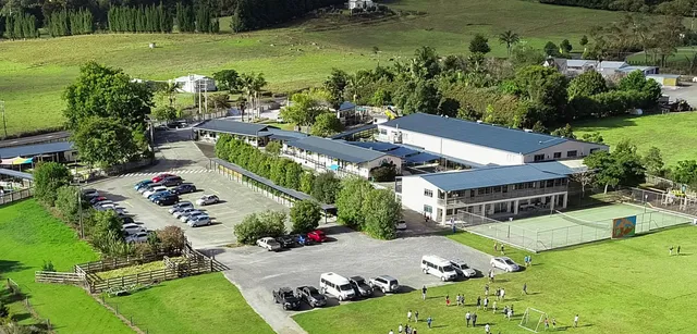 Il campus della Springbank School mostra diversi edifici, parcheggi con veicoli e colline verdi sullo sfondo.