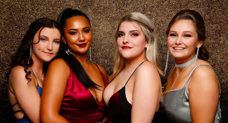 Quattro donne dall'aspetto diverso mettono in posa insieme su uno sfondo dorato nel campus del Waitakere College.