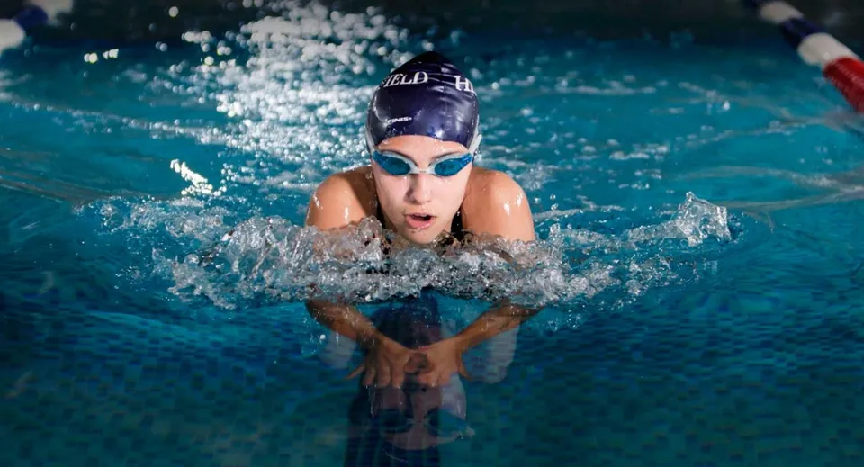 Una studentessa della Heathfield School a Ascot riemerge dall'acqua di una piscina limpida durante la lezione di nuoto.