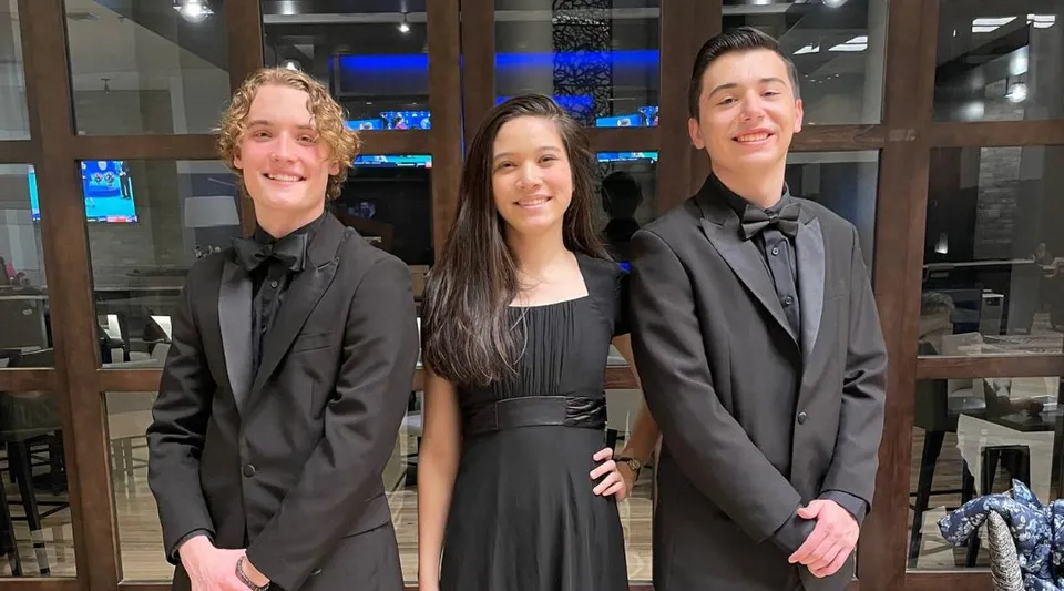 Tre persone in abito formale a un evento nel campus della The Vanguard School.