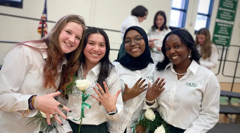 Un gruppo di studentesse sorridenti in divisa bianca posa insieme alla Laurel School.