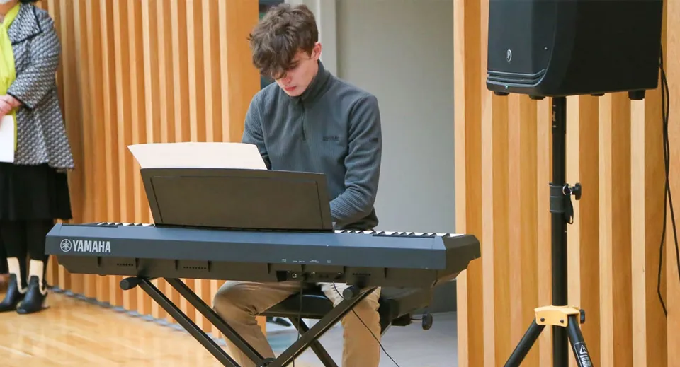 Una persona suona la tastiera nell'aula di musica della Glenstal Abbey School con pareti rivestite in legno.