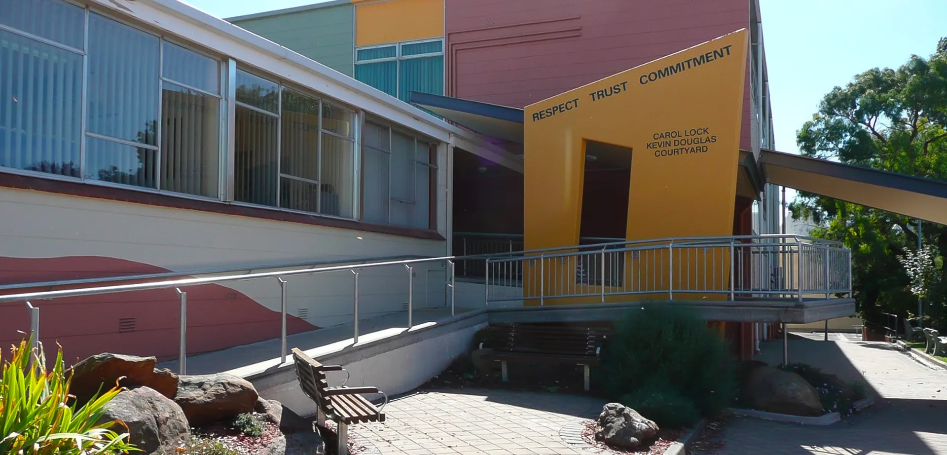 L'edificio moderno della Grant High School mostra un ingresso con rampa e un paesaggio naturale con pietre e piante.