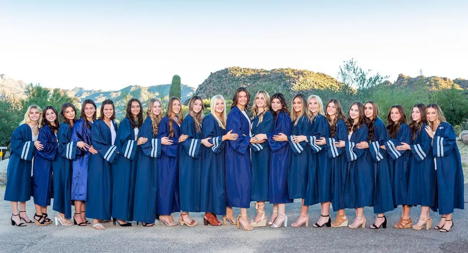Studentesse del Cave Creek Unified School District posano con la toga blu del diploma davanti a un paesaggio montano.