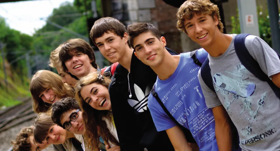 Un gruppo di studenti della Ardscoil Phadraig è insieme all'aperto e sorride davanti ad alberi ed edifici.