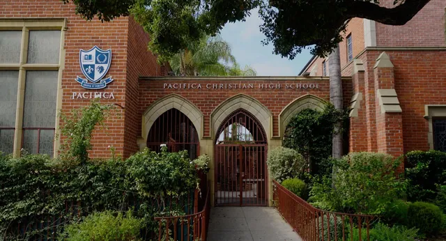 L'edificio in mattoni con ingressi ad arco della Pacifica Christian High School è circondato da una verde vegetazione.