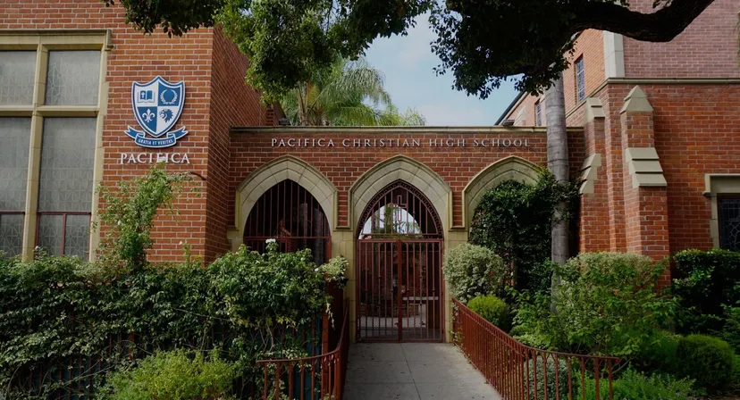 L'edificio in mattoni con ingressi ad arco della Pacifica Christian High School è circondato da una verde vegetazione.