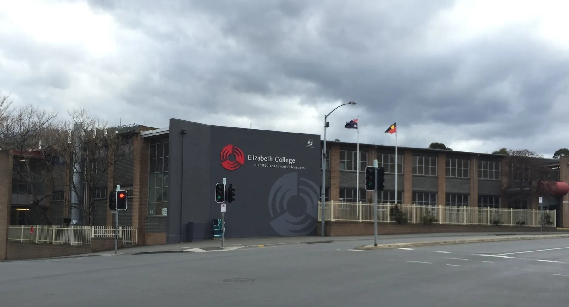L'edificio moderno dell'Elizabeth College con il logo sulla facciata sotto un cielo nuvoloso.