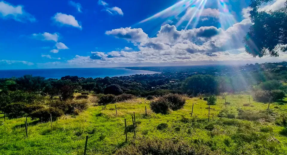 Un prato verde con vista su una città costiera e il cielo sopra il terreno del Plympton International College.