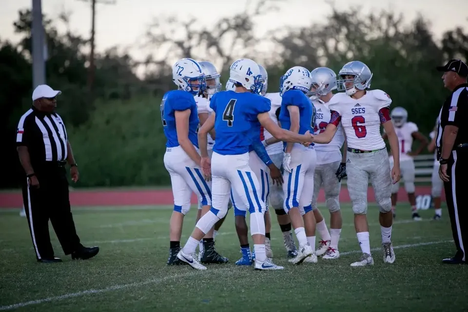 Giocatori di football americano della St. Stephen's Episcopal School si stringono la mano sul campo.