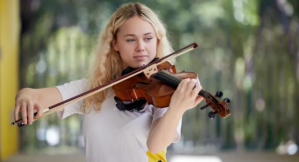 Una studentessa della Maroochydore State High School suona il violino nel verde.