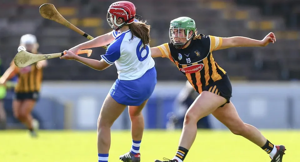 Due studentesse del Franciscan College Gormanston giocano una partita competitiva sul campo sportivo indossando divise sportive diverse.