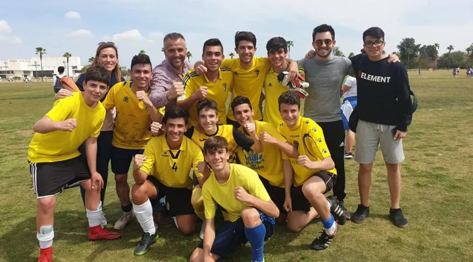 Un gruppo di studenti con maglie giallo-nere posa sul campo in erba del campus della scuola San Vicente de Paul.