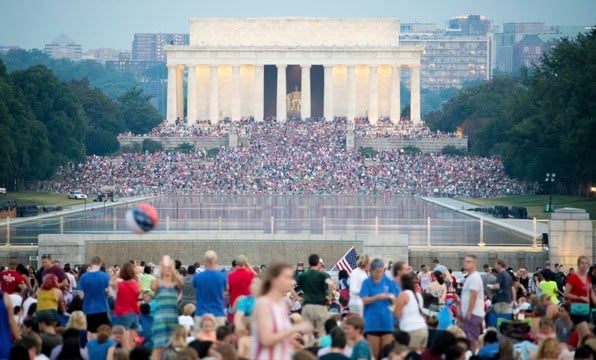 Multitud de personas congregadas frente al Monumento a Lincoln junto al estanque reflectante al atardecer