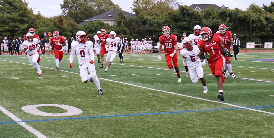 La squadra di football dei Cougars entra in campo alla St. John the Baptist High School con le maglie rosse.