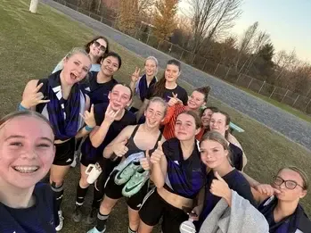 Selfie de un equipo femenino de fútbol celebrando en el campo al anochecer