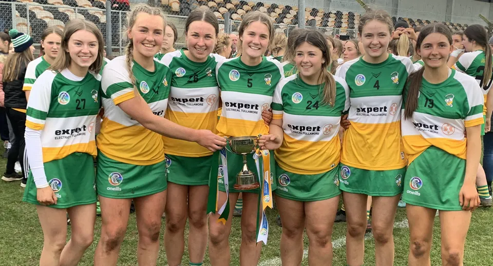 Gli studenti del Coláiste Naomh Cormac festeggiano nello stadio insieme con una coppa in mano.