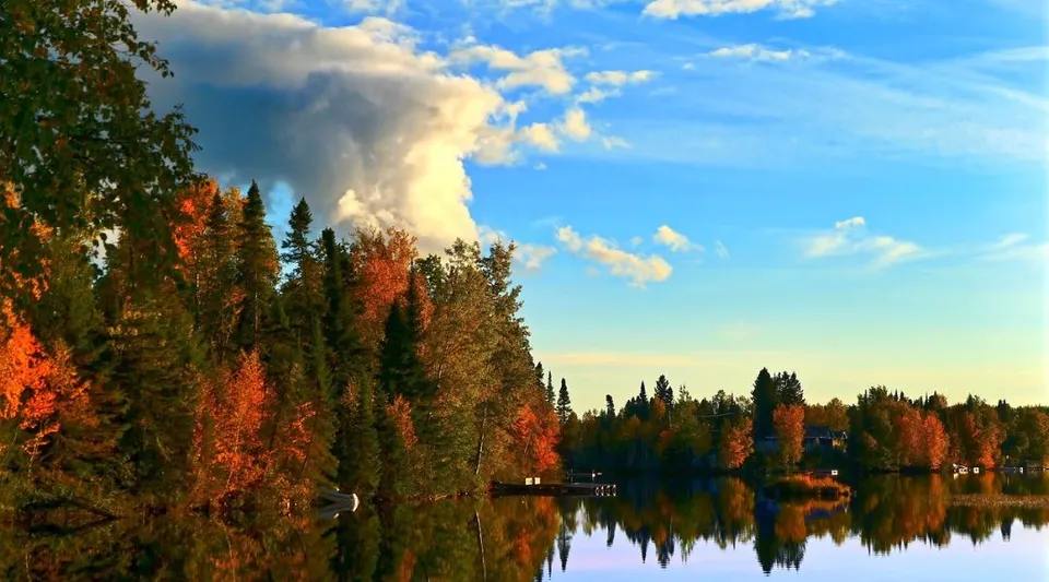 Un lago tranquillo con un paesaggio alberato autunnale e cielo nuvoloso sul terreno del Lower Canada College.