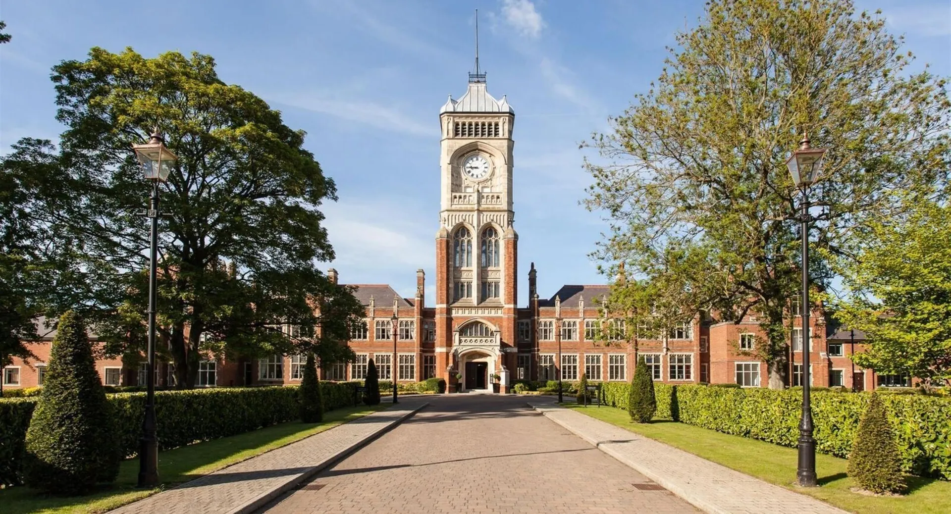 Si vede l'edificio principale storico della Royal Masonic School for Girls con un'alta torre dell'orologio nel campus curato.