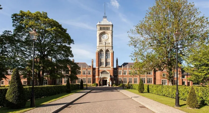 Si vede l'edificio principale storico della Royal Masonic School for Girls con un'alta torre dell'orologio nel campus curato.