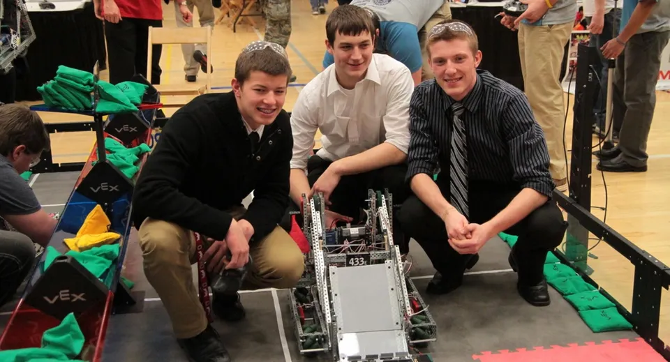 Studenti della Enver Creek Secondary School lavorano insieme a un robot in officina.