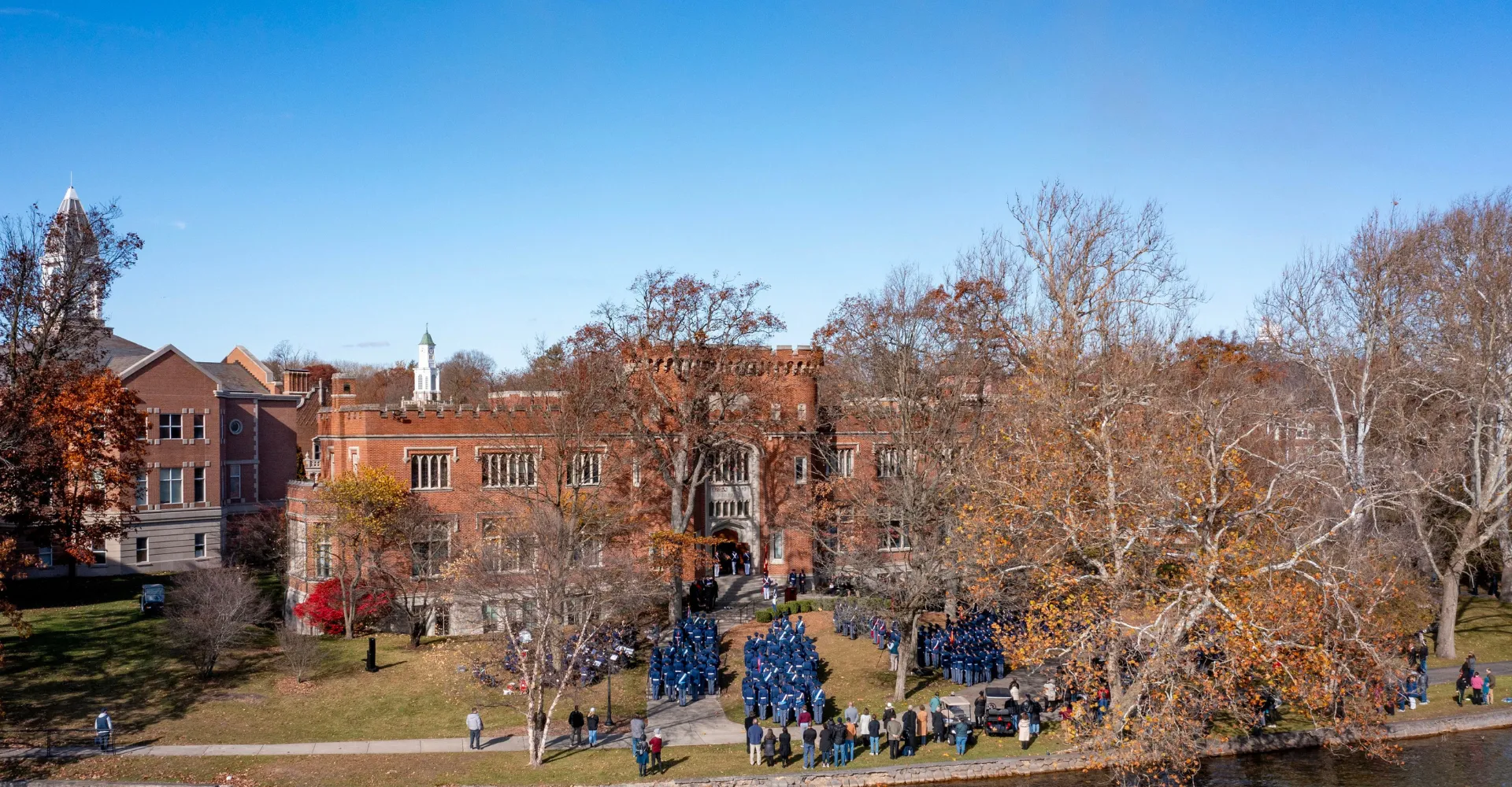 L'edificio storico simile a un castello della Indiana Private Highschool si vede sotto un cielo blu con alberi spogli e persone sul viale.
