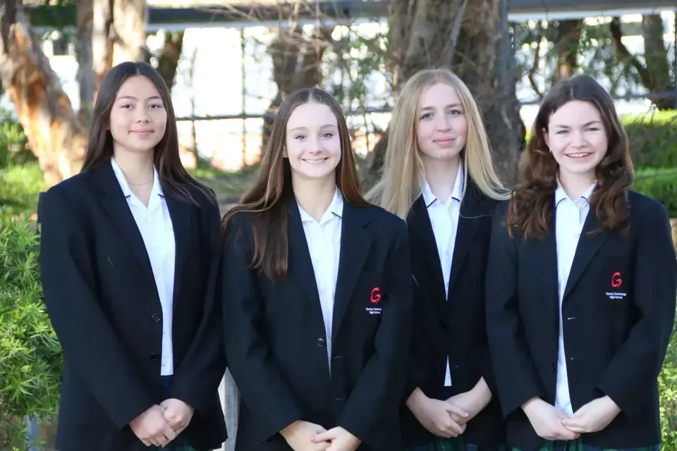 Quattro studentesse della Gymea Technology High School indossano la divisa scolastica e sorridono all'aperto.