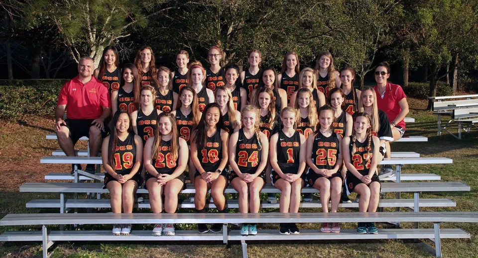 Un gruppo di giovani atlete della Orangewood Christian School seduto su tribune all'aperto davanti agli alberi.