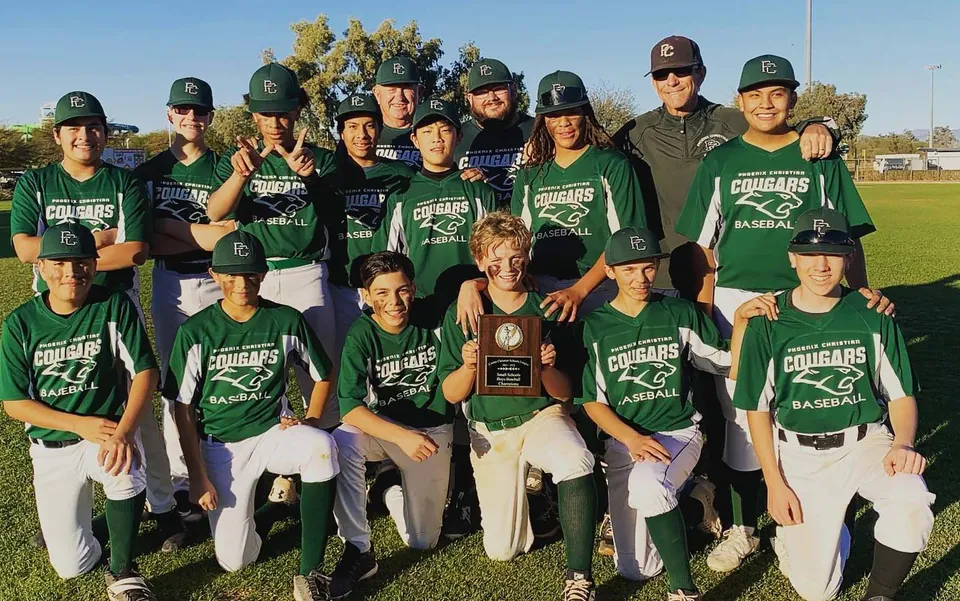 Studenti della Phoenix Christian Preparatory School posano insieme sul campo da baseball indossando divise verdi da baseball.
