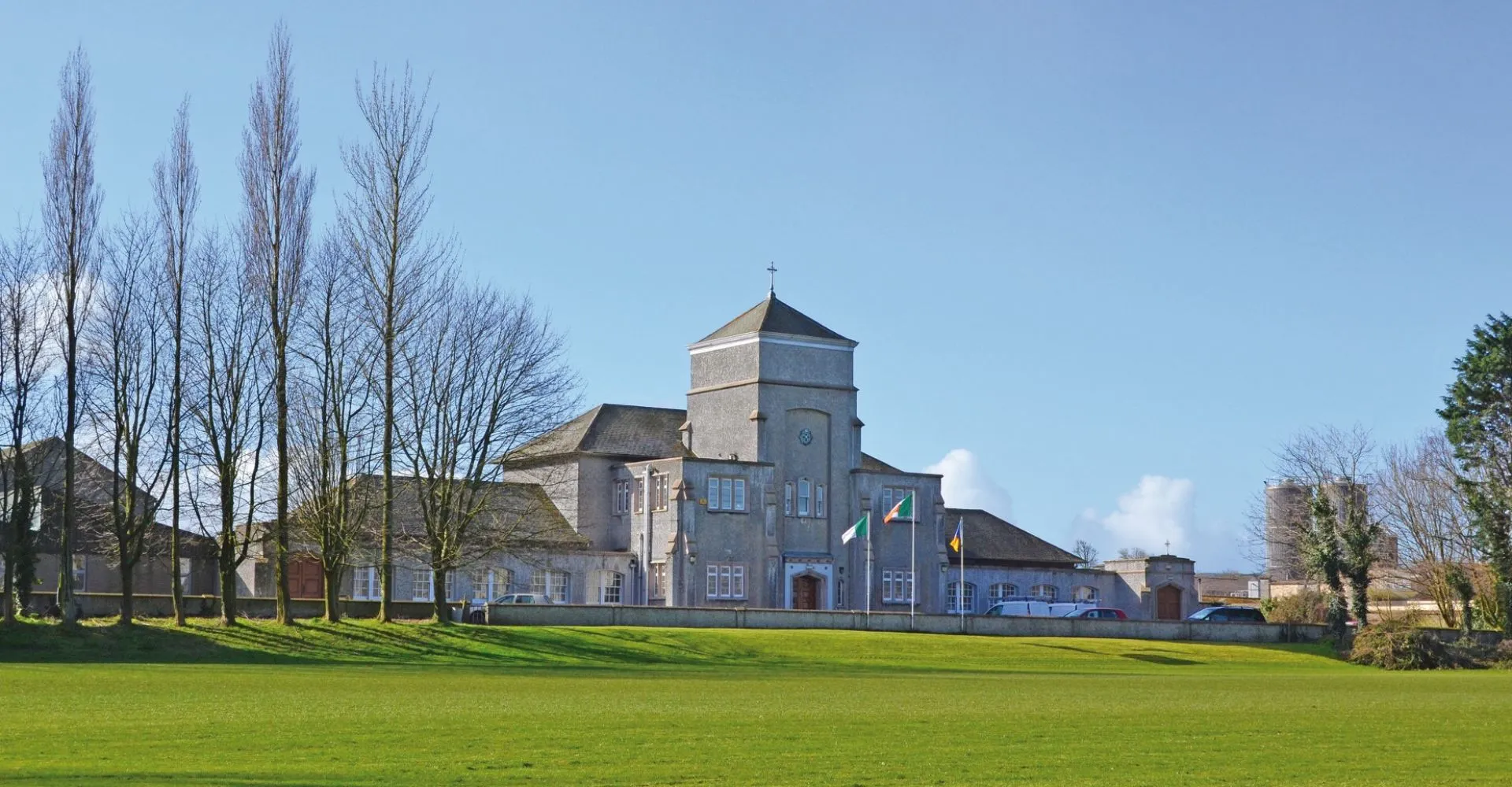 L'edificio principale storico della The Abbey School si trova davanti a un prato verde con alberi spogli sullo sfondo.