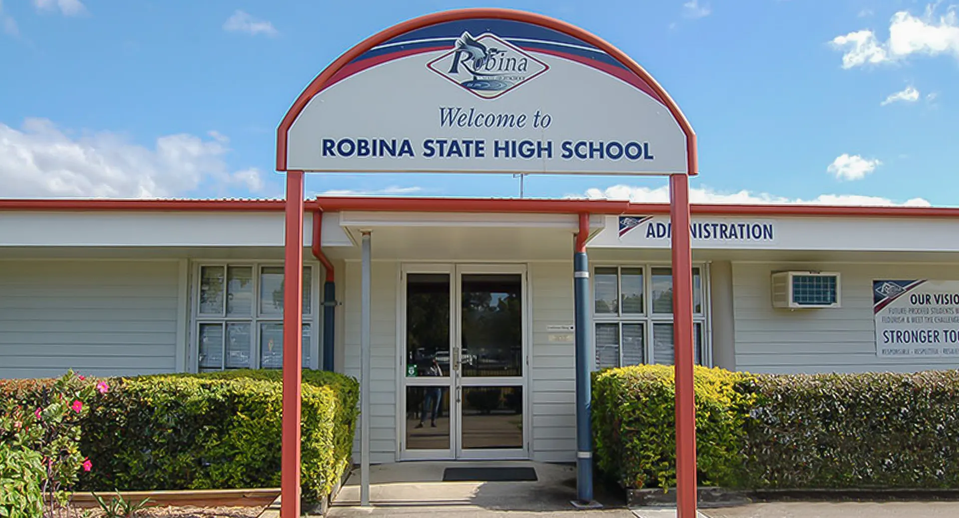 L'ingresso con un grande cartello di benvenuto e il logo della Robina State High School.