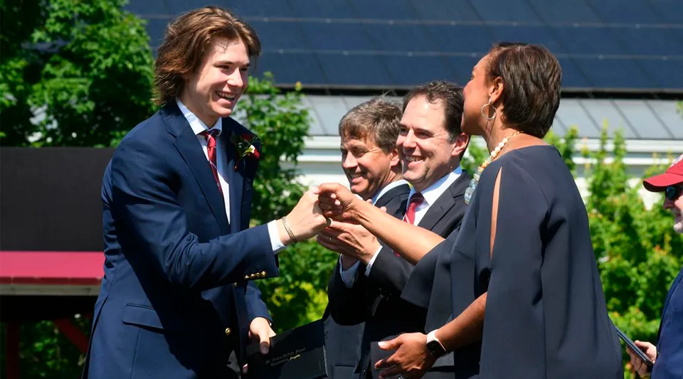 Un gruppo di uomini in abbigliamento formale si riunisce nel giardino della St. Anne's-Belfield School.