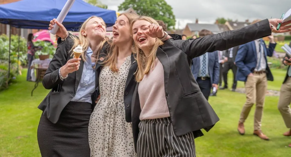 Un gruppo di studentesse della St. Felix School si scatta un selfie all'aperto davanti a una tenda e a un'area verde.