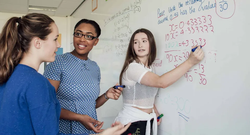 Tre studenti lavorano insieme a una whiteboard durante un'attività di apprendimento nel campus della Shrewsbury School.